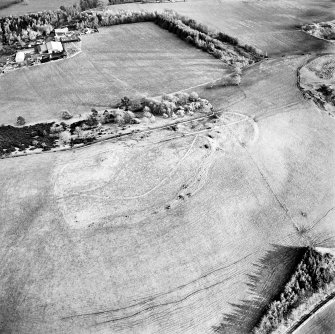 Oblique aerial view centred on the remains of the fort, settlement and cairn, taken from the WNW.