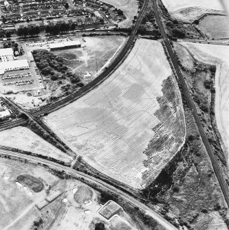 Raeburnfoot, oblique aerial view, taken from the SSW, centred on the bank barrow. Raeburnfoot Roman Fort, and enclosures at Kiln Syke, are visible in the bottom right-hand corner of the photograph.