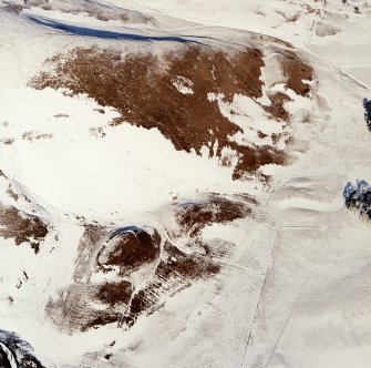 Oblique aerial view centred on the remains of the settlements, rig and enclosure with the remains of the forts adjacent, taken from the SSW.