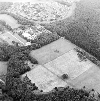 Oblique aerial view of Bo'ness, Kinneil, centred on the cropmarks of the Antonine Wall with a church and tower-house adjacent, taken from the NW.