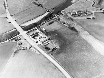Oblique aerial view centred on the road bridge and the remains of the motte and railway viaduct, taken from the E.