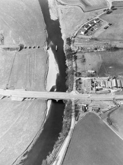 Oblique aerial view centred on the road bridge and the remains of the motte and railway viaduct, taken from the SE.