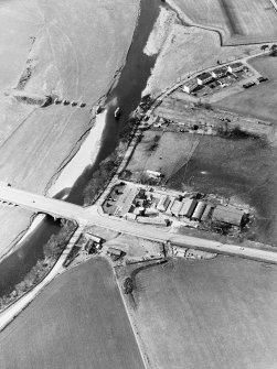 Oblique aerial view centred on the road bridge and the remains of the motte and railway viaduct, taken from the ESE.