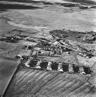 Tarbrax Shale-Oil Works, oblique aerial view, taken from the E, showing Tarbrax village in the centre of the photograph, and part of one of the bings of the shale-oil mine in the centre right.. An area of rig is visible at the bottom.