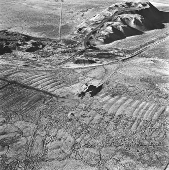 Tarbrax Shale-Oil Works, oblique aerial view, taken from the ENE, showing one of the massive shale bings associated with the shale-oil mine at the top of the photograph, with a tramway running alongside it to the left, and the Tarbrax Branch of the Caledonian Railway to the right. A second, smaller, shale bing overlies an area of rig in the bottom half.
