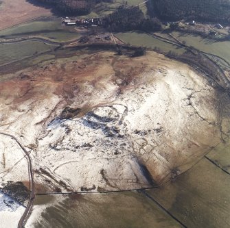 Oblique aerial view centred on the remains of the fort, settlements and field system with the farmsteading adjacent, taken from the N.