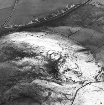 Oblique aerial view centred on the remains of the fort, settlements and field system, taken from the ENE.