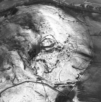 Oblique aerial view centred on the remains of the fort, settlements and field system, taken from the NE.