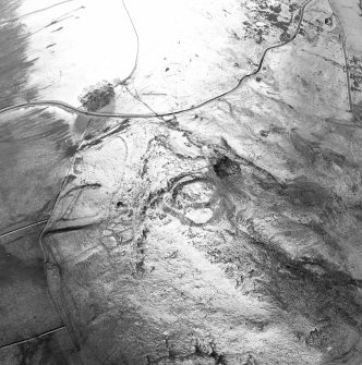 Oblique aerial view centred on the remains of the fort, settlements and field system, taken from the SW.