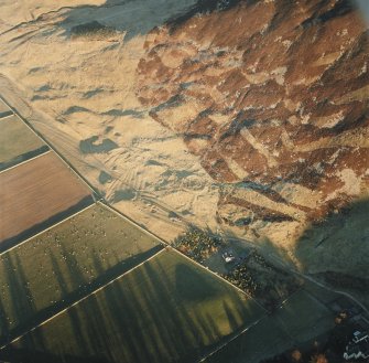 Oblique aerial view centred on the remains of the enclosure and scooped settlement, taken from the SW.