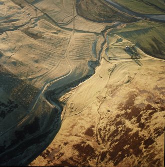 Oblique aerial view centred on the remains of the farmstead, buildings, rig and cultivation terraces with the remains of the possible settlement and enclosure adjacent, taken from the ENE.