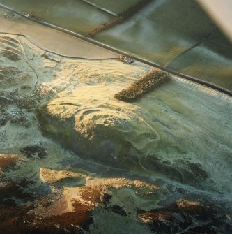 Oblique aerial view centred on the remains of the fort and castle with the remains of the cultivation terraces and enclosure adjacent, taken from the E.