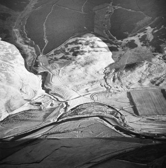 Oblique aerial view centred on the remains of the buildings, rig, cultivation terraces with the remains of the possible settlement and enclosure adjacent, taken from the NW.