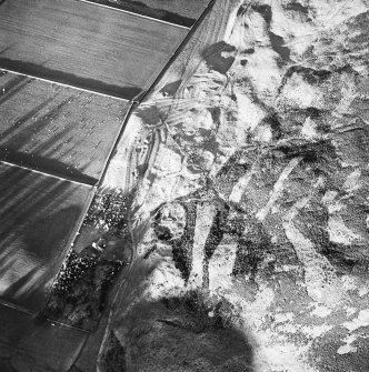 Oblique aerial view centred on the remains of the enclosure and scooped settlement with the remains of the sheepfold, cairn and cist adjacent, taken from the S.