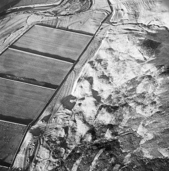 Oblique aerial view centred on the remains of the sheepfold, cairn and cist with the remains of the buildings, banks and enclosures adjacent, taken from the S.