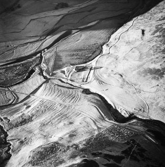 Oblique aerial view centred on the remains of the buildings, rig and cultivation terraces with the remains of the farmstead, possible settlement, enclosure and sheep shelter adjacent, taken from the ESE.