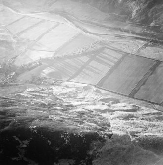 Oblique aerial view centred on the remains of the enclosure and scooped settlement with the remains of the sheepfold, cairn and cist adjacent, taken from the ENE.