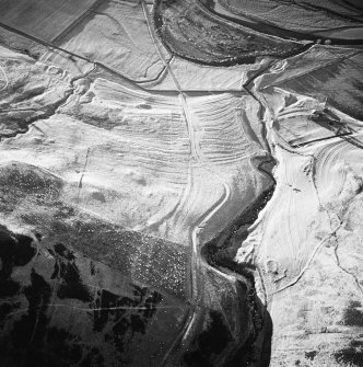 Oblique aerial view centred on the remains of the buildings, rig, cultivation terraces and farmstead with the remains of the enclosure and possible settlement adjacent, taken from the E.