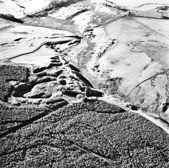 Oblique aerial view centred on the remains of the limekilns and quarry with farmhouse adjacent, taken from the ENE.