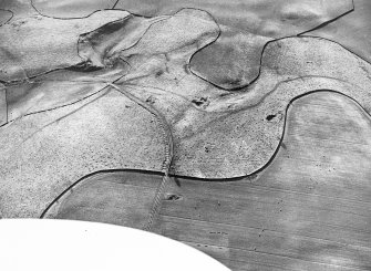 Oblique aerial view of the remains of the earthwork and pit-alignment, taken from the E.