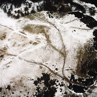 Oblique aerial view centred on the remains of the trenches with the palisaded settlement and rig adjacent, taken from the SW.