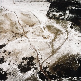 Oblique aerial view centred on the remains of the trenches with the palisaded settlement and rig adjacent, taken from the SSW.