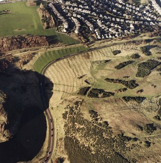 Oblique aerial view of Holyrood Park centred on the remains of rig with a quarry and ring-ditch adjacent, taken from the WSW.