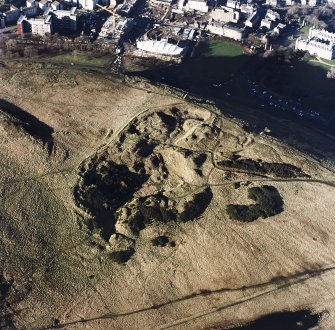 Oblique aerial view of Holyrood Park centred on the remains of quarries, taken from the SE.