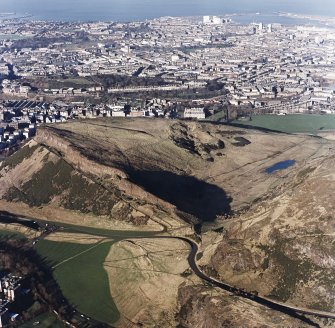 Oblique aerial view of Holyrood Park centred on the remains of quarries on Salisbury Crags with cultivation remains below, taken from the S.