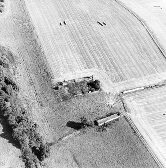 Oblique aerial view centred on the remains of the house with building adjacent, taken from the W.