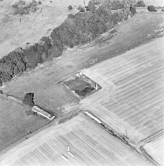 Oblique aerial view centred on the remains of the house with building adjacent, taken from the SSW.