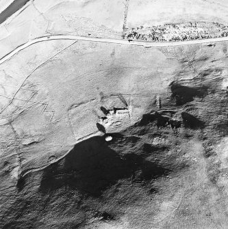 Oblique aerial view centred on the remains of the tower-house, buildings and enclosures, taken from the NW.