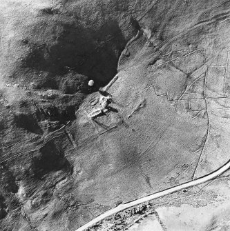 Oblique aerial view centred on the remains of the tower-house, buildings and enclosures, taken from the SE.