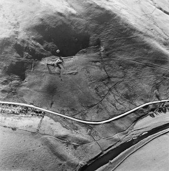Oblique aerial view centred on the remains of the tower-house, buildings and enclosures, taken from the ESE.