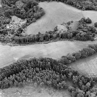 Oblique aerial view of Braidwood centred on linear cropmarks with two churches and a session-house visible in the upper left, taken from the N.