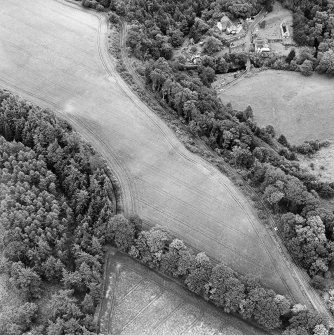 Oblique aerial view of Braidwood centred on linear cropmarks with two churches and a session-house visible in the upper right, taken from the NW.