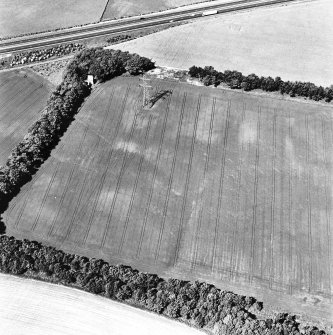 Castlesteads, oblique aerial view, taken from the ESE, centred on the cropmarks of a pit alignment and enclosure. A dovecot is visible in the top left-hand corner of the photograph.