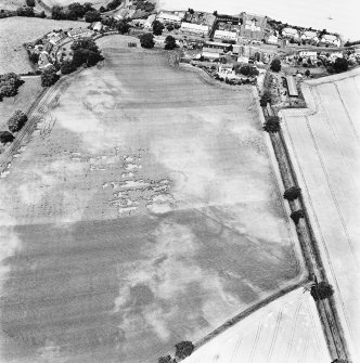 Carrington Mill, enclosure: oblique aerial view taken from the SE, centred on the cropmarks of an enclosure.  The village (burgh) of Carrington is visible in the top right of the photograph.