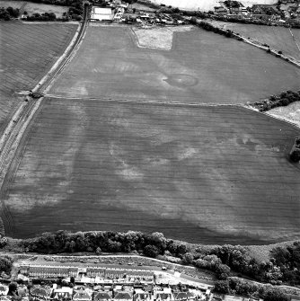 Brunstane, oblique aerial view, taken from the NW, centred on the cropmarks of an enclosure, coal pits and shaft, a possible enclosure and rig.  Other cropmarks are also visible.