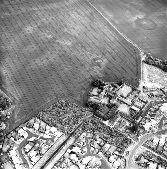 Brunstane, oblique aerial view, taken from the E, centred on the cropmarks of an enclosure, coal pits and shaft, a possible enclosure and rig.  Other cropmarks are also visible.  Brunstane House is visible in the right centre of the photograph.