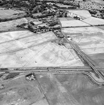 Westfield, Inveresk, oblique aerial view, taken from the SSE, centred on the cropmarks of a cursus monument and internal ring-ditch. The cursus is bisected by the cropmark of a dismantled mineral railway.