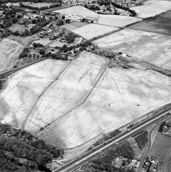 Westfield, Inveresk, oblique aerial view, taken from the SSW, showing the cropmarks of a cursus monument in the right half of the photograph and internal ring-ditch. The cursus is bisected by the cropmark of a dismantled mineral railway.