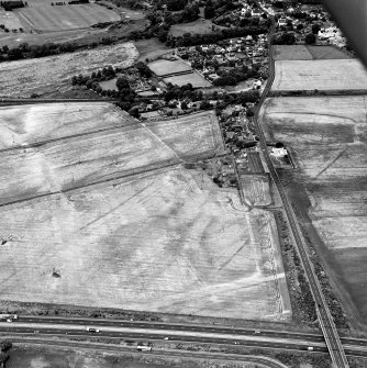 Westfield, Inveresk, oblique aerial view, taken from the SE, centred on the cropmarks of a cursus monument and internal ring-ditch. The cursus is bisected by the cropmark of a dismantled mineral railway. Cropmarks of a field-system are visible in the top right-hand corner.