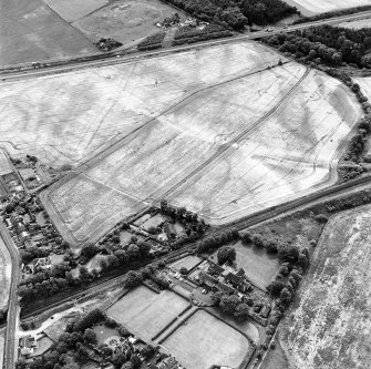 Westfield, Inveresk, oblique aerial view, taken from the N, showing the cropmarks of a cursus monument in the left half of the photograph. The cursus is bisected by the cropmark of a dismantled mineral railway.