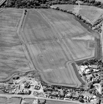 Oblique aerial view centred on the cropmarks of the mineral railway, cursus and Roman temporary camp, taken from the NE.