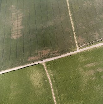 Howe Mire and Barbachlaw, oblique aerial view, taken from the NE, showing cropmarks which include those of an enclosure in the centre of the photograph, a possible enclosure in the bottom right-hand corner, and a settlement in the top right-hand corner.