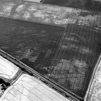 Howe Mire, oblique aerial view, taken from the NW, showing the cropmarks of a series of coal pits in the top half of the photograph. Cropmarks of a settlement are visible in the top left-hand corner. The photograph is centred on a linear cropmark and indeterminate marks.