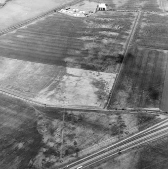 Oblique aerial view centred on the cropmarks of the coal-pits and field-boundary with other cropmarks, including those of the settlement, adjacent, taken from the SSW.