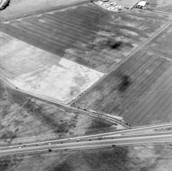 Oblique aerial view centred on the cropmarks of the coal-pits and field-boundary with other cropmarks including those of the settlement, the linear cropmarks, the ring-ditch, pits and rig adjacent adjacent, taken from the S.