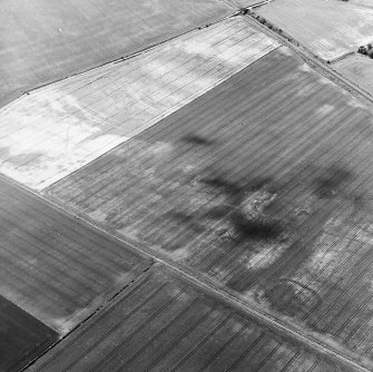 Oblique aerial view centred on the cropmarks of the coal-pits and field-boundary with other cropmarks, including those of the settlement, adjacent, taken from the E.